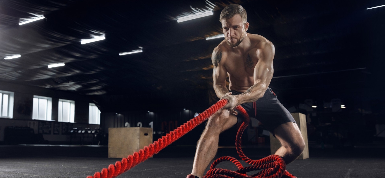 young healthy man, athlete doing exercise with the ropes in gym