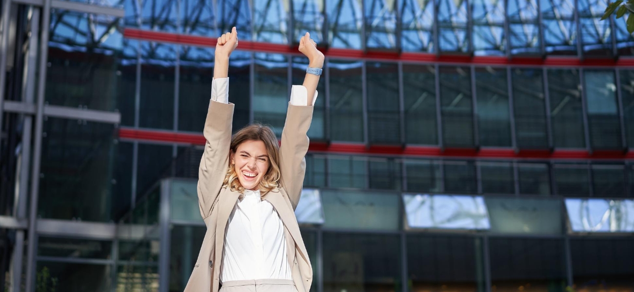 happy businesswoman dancing on street raising hands up